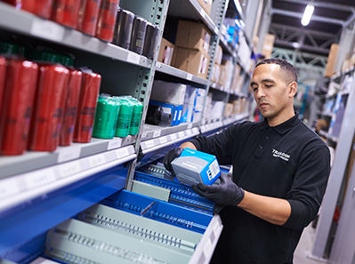 Warehouse worker examines products beside metal shelving